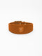 A wide cognac nubuck leather dog collar from Manifattura VALOR featuring a gold-embossed V shield logo patch and polished brass hardware rivets.