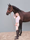 Rider standing beside a dark bay horse wearing a premium brown leather halter with matching lead rope.