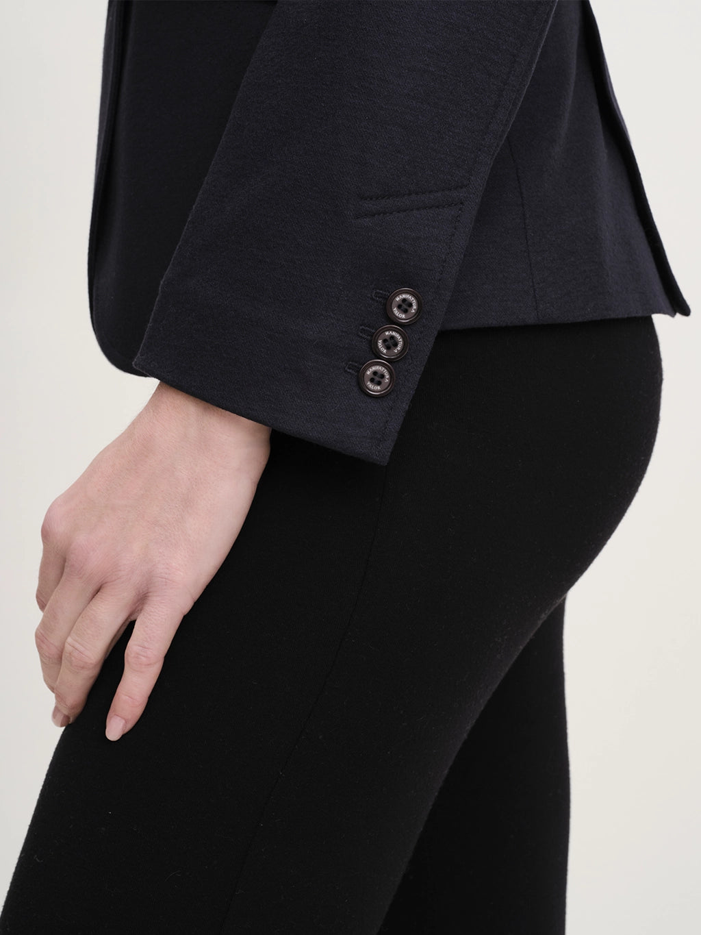Close-up of a navy merino wool riding jacket sleeve featuring three detailed corozo buttons on the cuff.
