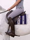 A person in grey riding gear sits on a white horse, featuring a brown leather saddle and a grey felt saddle pad with navy blue vertical stripes.
