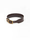 A dark brown stitched leather dog collar from Manifattura VALOR featuring a solid brass roller buckle, an integrated keeper loop, and a subtly embossed V shield monogram logo.