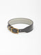 A wide slate grey leather dog collar from Manifattura VALOR featuring a light grey padded lining, a solid brass roller buckle, and a subtly embossed V shield monogram logo.