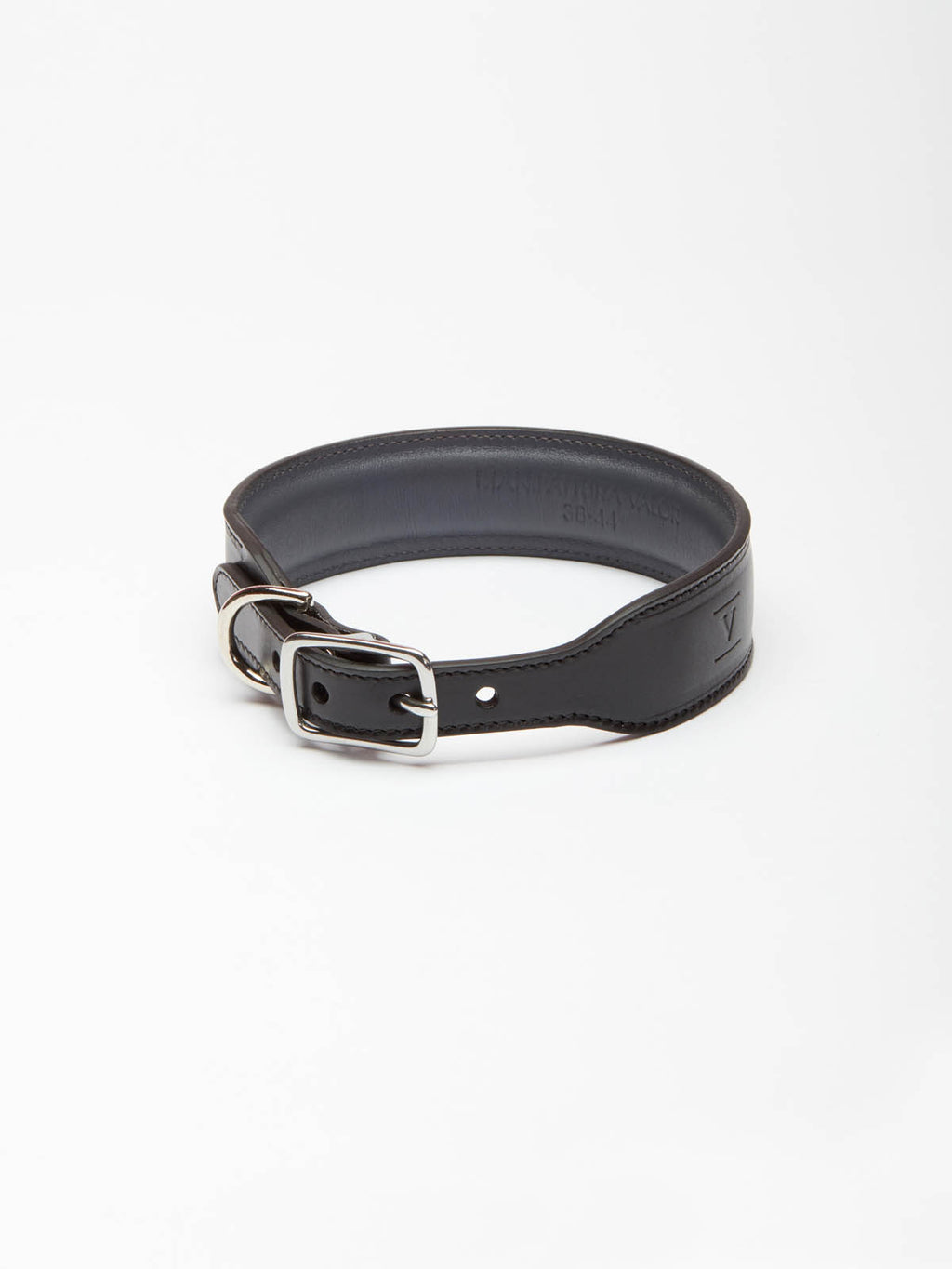 A wide black leather dog collar from Manifattura VALOR featuring silver hardware, a roller buckle, and a subtly embossed V shield monogram logo.
