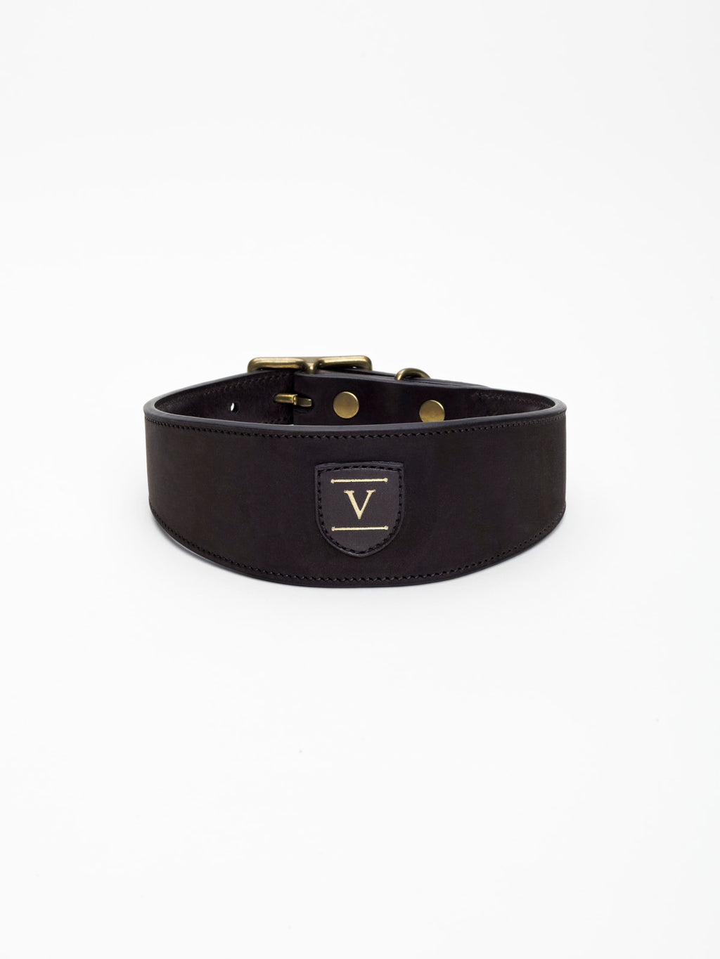 A wide black nubuck leather dog collar from Manifattura VALOR featuring a gold-embossed V shield logo patch and polished brass hardware rivets.