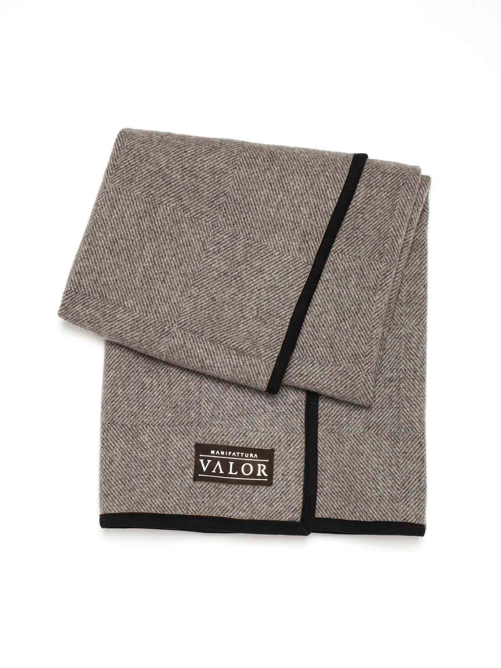A folded brown and beige herringbone wool blanket featuring a black suede border and a Valor leather patch.