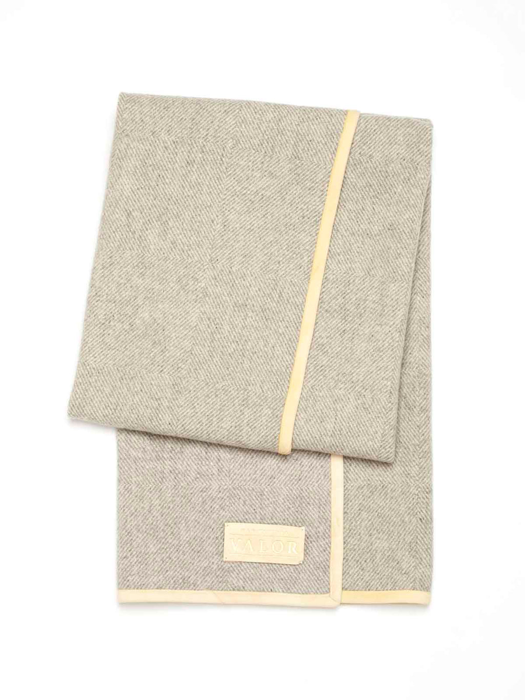 Manifattura Valor folded wool blanket in grey herringbone weave with cream leather trim and logo label.