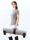 Woman in equestrian riding attire carrying rolled grey wool felt Manifattura Valor dog bed with black leather straps.