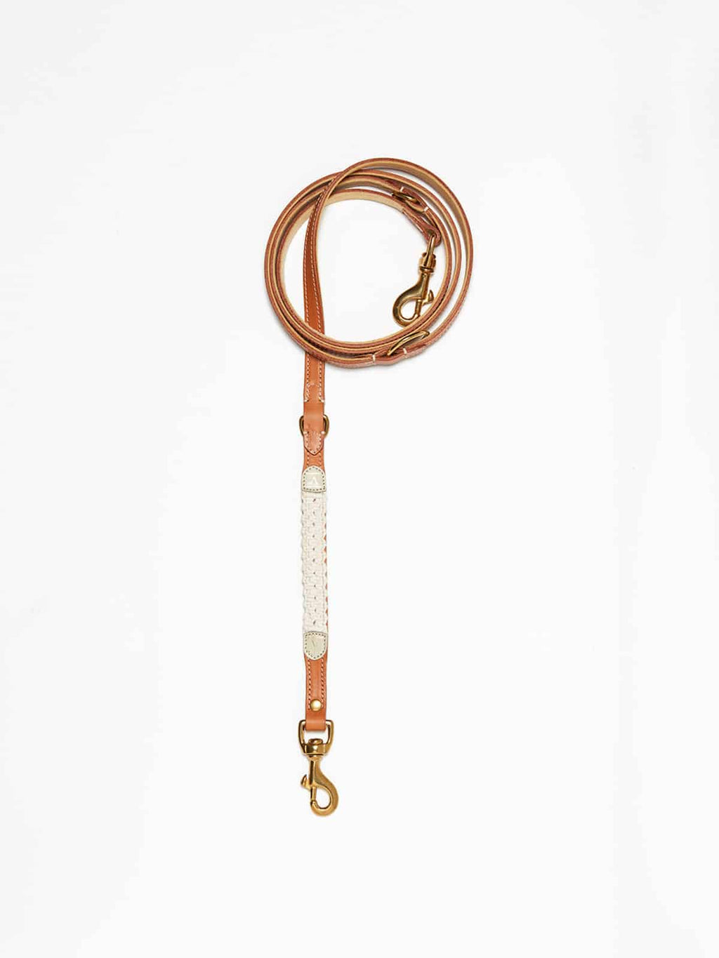 A cognac leather dog lead from Manifattura VALOR featuring an off-white natural hand-knotted macramé accent section and brass swivel snap hooks.