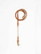 A cognac leather dog lead from Manifattura VALOR featuring an off-white natural hand-knotted macramé accent section and brass swivel snap hooks.